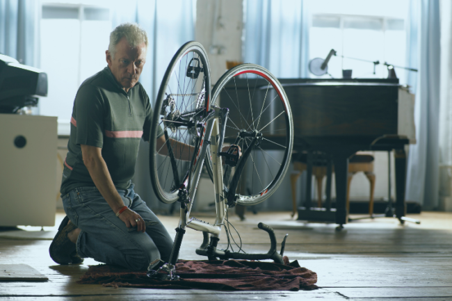Older man kneeling by bicycle