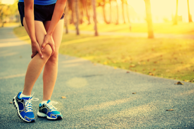 Sporty woman holding knee in pain