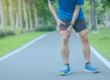 Man holding knee in pain whilst running