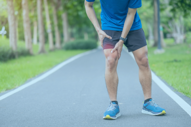 Man holding knee in pain whilst running