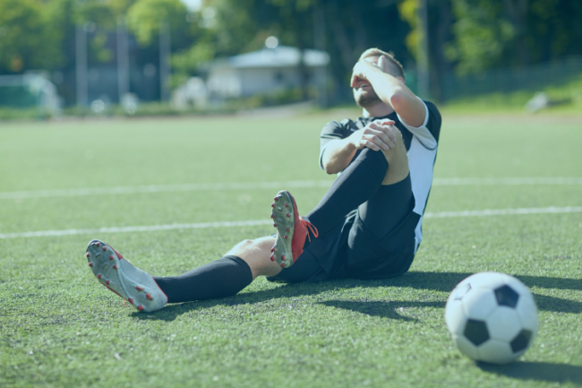 Football player on ground holding knee in pain