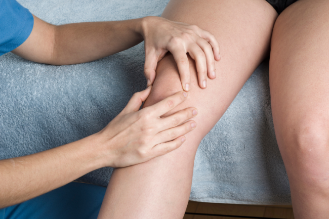 Doctor looking at patient's knee to determine patellar tendonitis