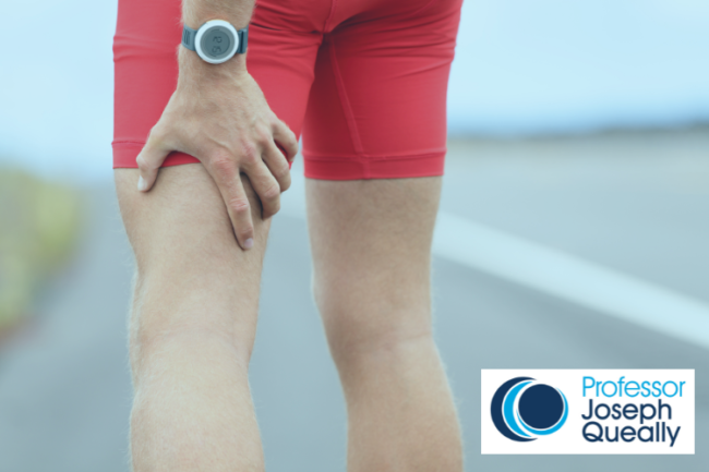Man in red running shorts holding hamstring