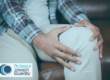Man sat on sofa holding his knee